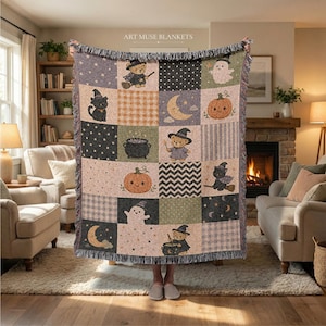 May include: A woven throw blanket featuring a grid of Halloween-themed squares with illustrations of teddy bears in witch hats, black cats, pumpkins, ghosts, crescent moons, and cauldrons, finished with a fringed edge and the text ART MUSE BLANKETS.