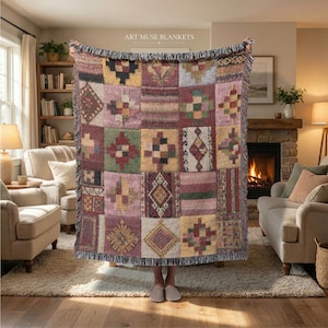 May include: A woven throw blanket featuring a patchwork design of various geometric patterns in shades of pink, green, yellow, and brown. The blanket has a fringed edge and displays the text ART MUSE BLANKETS at the top center.