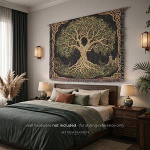 Puede incluir: Un tapiz de pared tejido rectangular que presenta un gran árbol central con ramas y raíces doradas sobre un fondo oscuro. El borde muestra intrincados patrones de nudos. El texto en la imagen dice: wall hardware NOT INCLUDED - for styling reference only, ART MUSE BLANKETS.