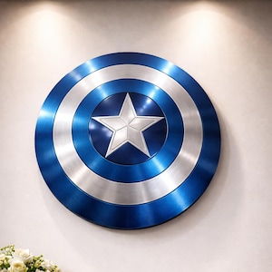 May include: A Captain America shield, featuring a blue, silver, and white color scheme. The shield is circular with a central white star and concentric rings of blue and silver. It is mounted on a white wall.