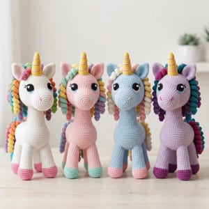 May include: Four crocheted unicorn dolls standing in a row. Each unicorn features a solid-colored body in white, pink, blue, or purple, a yellow spiral horn, and a multi-colored mane and tail made of small, tightly coiled yarn loops.