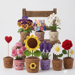 Può includere: Una collezione di piante in vaso all'uncinetto con vari fiori tra cui viole del pensiero, un girasole, lavanda, una rosa e margherite. Ogni pianta è in un piccolo vaso all'uncinetto beige o colorato con un viso sorridente ricamato.