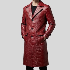Può includere: Un cappotto lungo rosso scuro con una trama testurizzata in pelle di coccodrillo. Il cappotto presenta un bavero dentellato, una chiusura frontale a tre bottoni, maniche lunghe con polsini abbottonati e due ampie tasche con patta sul davanti.