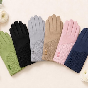 Könnte beinhalten: Eine Auswahl von sechs Handschuhen in Olivgrün, Schwarz, Hellgrau, Beige, Hellrosa und Marineblau. Jeder Handschuh hat einen glatten oberen Teil, ein strukturiertes Strickbündchen und zwei kleine runde Knöpfe am Handgelenk.