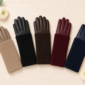 Può includere: Cinque paia di guanti disposti in fila, ognuno caratterizzato da una sezione della mano in pelle liscia e un lungo polsino in maglia a coste. I colori da sinistra a destra sono beige, nero, marrone scuro, bordeaux e blu navy.