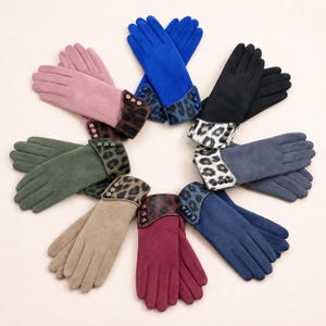 May include: A collection of eight pairs of gloves arranged in a circle, each featuring a solid color suede-like finish, a leopard print cuff, and three decorative buttons along the side of the wrist in shades of blue, black, pink, green, and red.