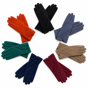 May include: A collection of six pairs of gloves arranged in a circle, each featuring a soft texture and a diagonal cuff detail adorned with four matching buttons. The colours include black, orange, blue, green, navy, burgundy, and tan.