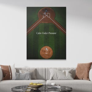 Pode incluir: Uma impressão de arte de parede retangular com uma vista aérea de um campo de beisebol com um diamante de grama verde e montes de terra marrom. O texto "Calm Under Pressure" está impresso em branco no centro do campo entre o arremessador e a base.