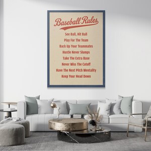 Puede incluir: Un cuadro decorativo rectangular con el texto rojo Baseball Rules en la parte superior, seguido de una lista de ocho frases relacionadas con el béisbol en rojo sobre un fondo beige claro, todo dentro de un marco azul oscuro.