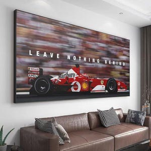 May include: A rectangular wall art print featuring a red Formula One race car in motion on a track. The car displays white logos including Marlboro, Shell, and AMD. The text LEAVE NOTHING BEHIND is printed in white capital letters above the vehicle.