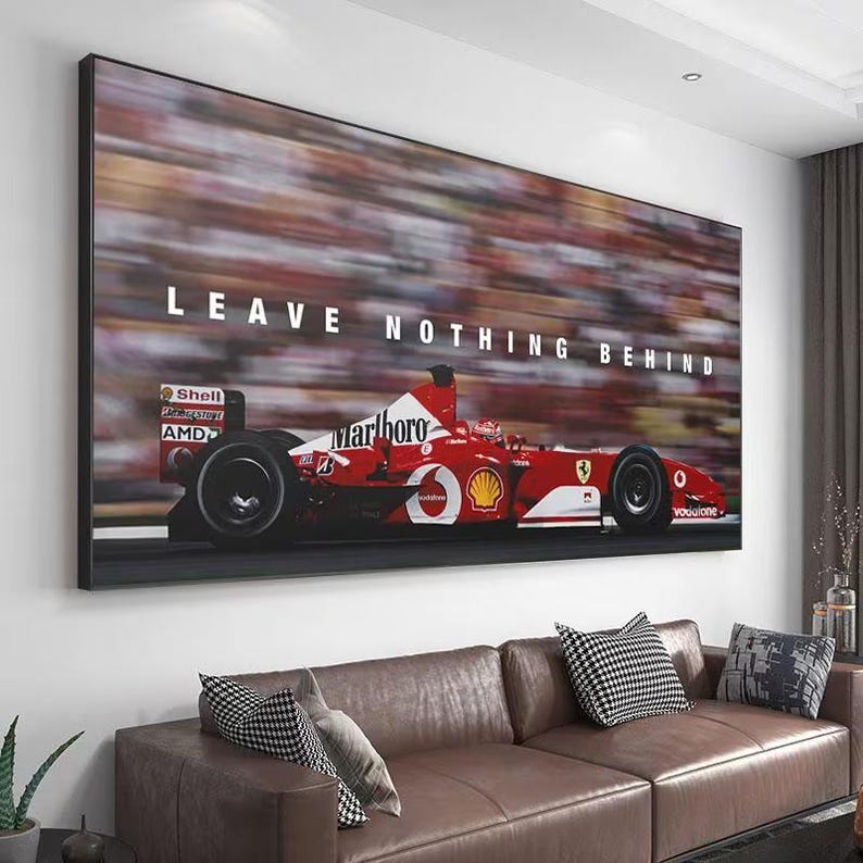 May include: A rectangular wall art print featuring a red Formula One race car in motion on a track. The car displays white logos including Marlboro, Shell, and AMD. The text LEAVE NOTHING BEHIND is printed in white capital letters above the vehicle.