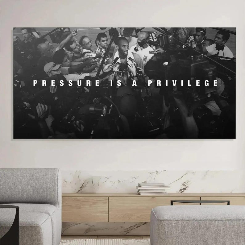 Op de afbeelding: Een rechthoekige zwart-wit wandkunstprint met een menigte fotografen en verslaggevers rondom een centrale figuur, met de dikgedrukte witte tekst PRESSURE IS A PRIVILEGE horizontaal gecentreerd in het midden van de afbeelding.