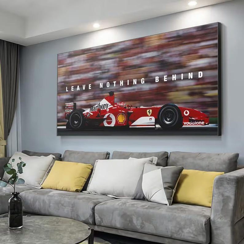 May include: A rectangular wall art print featuring a red Formula One race car in motion on a track. The car displays white branding logos and the text LEAVE NOTHING BEHIND in bold white capital letters against a blurred background of spectators.
