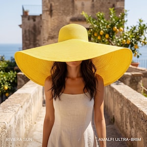 May include: A bright yellow wide-brimmed sun hat with a textured woven design. The hat features a rounded crown and a very large, flat brim. The text RIVIERA SUN AMALFI ULTRA-BRIM is printed in white at the bottom corners of the image.
