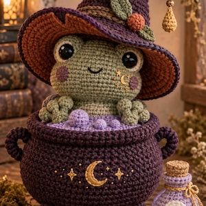 May include: A crocheted green frog wearing a purple pointed hat with a small orange berry and green leaves, sitting inside a dark purple crocheted cauldron filled with light purple bubbles. A small light purple potion bottle sits nearby.