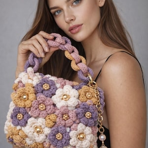 Puede incluir: Bolso de mano de ganchillo con diseño floral en tonos lavanda, crema, dorado y rosa. Tiene un asa de cadena y una cadena dorada con detalles de perlas. Un accesorio único y elegante, hecho a mano.
