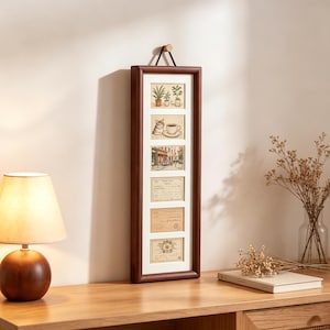 May include: A vertical rectangular dark wood wall frame featuring six stacked white mat openings. The artwork displays illustrations of potted plants, a cat with a coffee cup, a street scene, and three vintage-style documents with handwritten text.