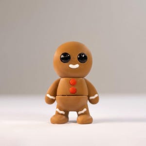 May include: A brown gingerbread man figurine with black eyes, a white smile, and two red buttons. The arms and legs have white icing details. The figurine is standing on a white surface.