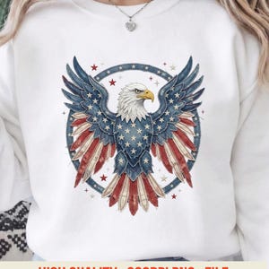 Op de afbeelding: Witte sweatshirt met een gedetailleerde afbeelding van een Amerikaanse adelaar met uitgespreide vleugels. Het ontwerp van de adelaar bevat de Amerikaanse vlag, met sterren en strepen. De tekst "HIGH QUALITY . 300DPI PNG . FILE" staat onderaan.