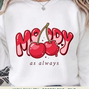 May include: White sweatshirt with a red and pink graphic of the word "MOODY" with two cherries and the phrase "as always". The cherries have a bite taken out of one. The sweatshirt has a crew neck.
