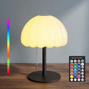 以下が含まれることがあります： キノコ型のテーブルランプ。発光するリブ付きのオフホワイトのシェード、黒い円筒形の支柱、円形の黒いベースを備えています。シェードからは銀色のプルチェーンが下がっています。垂直の虹色のカラーバーとリモコンが含まれています。