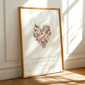 Könnte beinhalten: Ein gerahmter Druck mit einem herzförmigen Blumenarrangement in Rosa- und Weißtönen. Der Druck enthält den Text "STRENGTH AND HONOR ARE HER CLOTHING SHE SHALL REJOICE IN TIME TO COME Proverbs 31:25". Der Rahmen ist hellbraun.