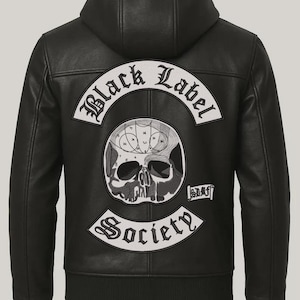Pode incluir: Casaco de couro preto com capuz e um grande patch nas costas. O patch apresenta um design de caveira com as palavras "Black Label Society" em uma fonte gótica. O casaco tem bainha e punhos canelados.