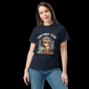 May include: Navy blue t-shirt with a cartoon monkey and baby monkey illustration. The graphic includes the text "TEAM PUNCH - PI DAY" and mathematical symbols. The monkeys are holding a pie. The shirt is made of a soft material.