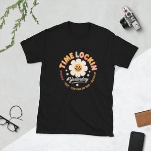 Peut inclure: T-shirt noir avec un motif de marguerite et les mots "Time Lockin'" et "#Yesterday" dans une police rétro. Le motif comprend les phrases "Stock, Test, You can do this, Casino".