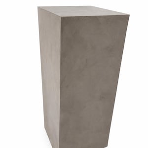 Puede incluir: Un pedestal gris rectangular con un diseño ligeramente cónico. El material similar al hormigón tiene una superficie texturizada. La parte superior es plana y cuadrada. Adecuado para exhibir plantas u objetos decorativos.