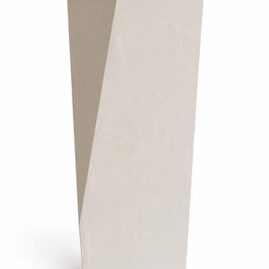 May include: A tall, off-white floor vase with a geometric, angular silhouette. The surface features a subtle, textured finish with visible brushstrokes or plaster-like markings, creating a matte appearance across the entire vertical structure.