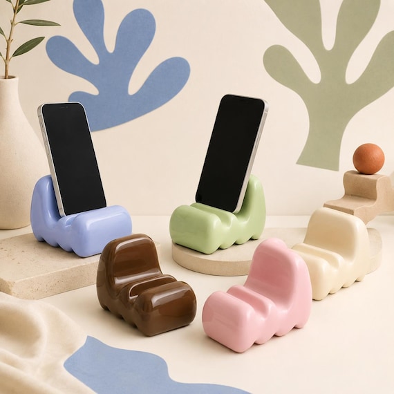 A $3,600 Matisse-inspired sculptural resin sofa acting as a phone stand — absurdly extra, dopamine-core art object that doubles as a desk accessory.