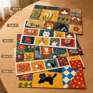 May include: Five rectangular mats with patchwork designs. Each mat features a different pattern of squares with floral and cat illustrations. The mats are in shades of yellow, green, red, and blue. The mats are stacked on a wooden table.