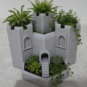 May include: A grey speckled concrete planter shaped like a castle with three tall towers and a lower front courtyard. The structure features arched windows, a central staircase leading to a doorway, and multiple planting areas filled with green plants.