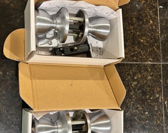 Manilla de puerta Kwikset con entrada sin llave, acabado níquel satinado y manija redonda.