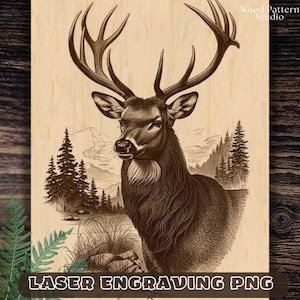 Puede incluir: Un panel de madera de color claro con una ilustración grabada con láser en marrón oscuro de un ciervo con grandes astas. La escena incluye un bosque con pinos, montañas y un pequeño cuerpo de agua. El texto Wood Pattern Studio es visible.