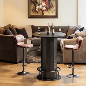 May include: A dark brown, round bar table with a dark brown wooden base and a metal footrest. Two brown leather bar stools with metal bases are positioned on either side of the table. Two bottles of wine and two wine glasses are on the table.