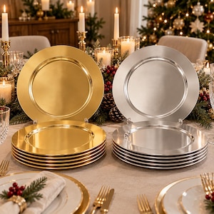 May include: A set of round charger plates featuring a smooth, metallic finish. The collection includes several gold-toned plates stacked on the left and several silver-toned plates stacked on the right, each with a wide, flat rim.