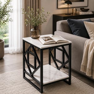 May include: A square side table featuring a white faux marble top and a lower shelf, supported by a black metal frame with geometric diamond-shaped side panels. An open book rests on the top surface, and a glass vase with greenery sits nearby.