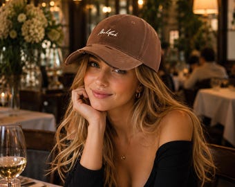 May include: A brown baseball cap with a distressed brim and the word New York embroidered in white cursive script on the front panel. The cap features a structured crown, a curved visor, and a classic six-panel design with ventilation eyelets.