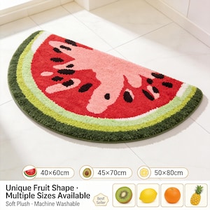May include: A semi-circular bath mat shaped like a watermelon slice, featuring a red center with black seeds, a light pink inner ring, and a dark green outer rind. The mat is displayed with text indicating available sizes of 40x60cm, 45x70cm, and 50x80cm.