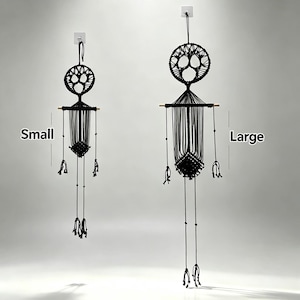 May include: Two black macrame wall hangings, labeled Small and Large, featuring a circular top section, a horizontal wooden dowel, and a central knotted diamond pattern with long dangling cords and beads hanging from the sides and bottom.