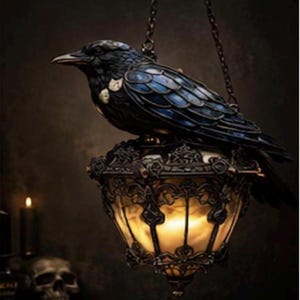 Puede incluir: Una lámpara colgante decorativa con un cuervo negro posado sobre una linterna ornamentada de color bronce. El cuervo tiene detalles azules y blancos en sus alas. La linterna tiene una luz cálida y brillante en su interior y está suspendida por una cadena.