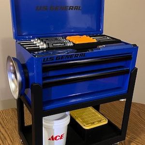 May include: A blue US GENERAL tool chest with an open top, revealing tools. The chest has black accents and sits on a black frame. A white bucket with the ACE logo and a yellow tray are on the bottom shelf.