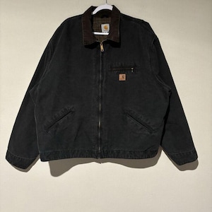 May include: Black work jacket with a brown corduroy collar and a full-length zipper. The jacket has two front pockets and a small square logo patch on the chest. The jacket is hanging on a white hanger.