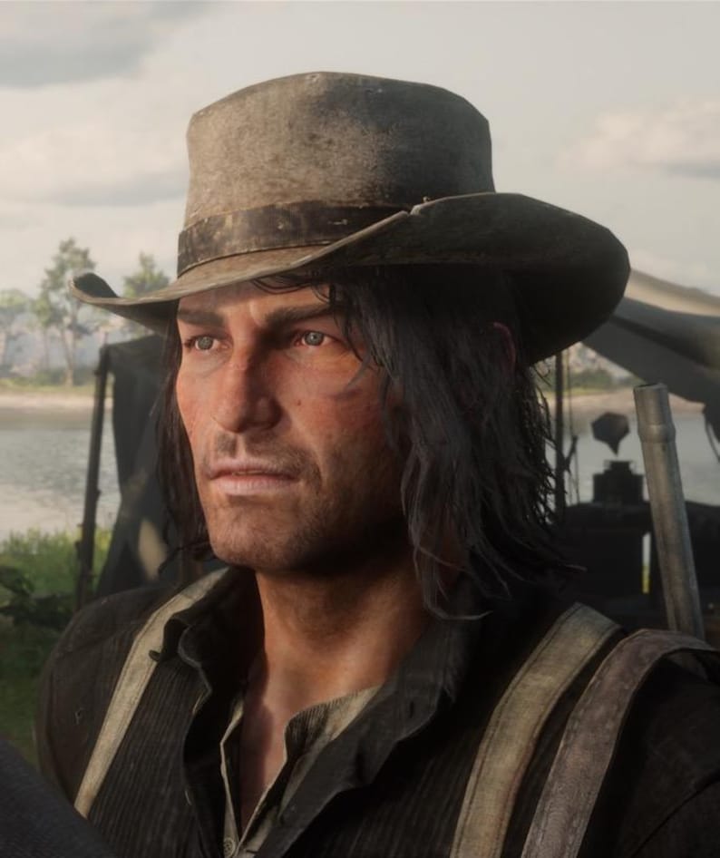 May include: A man wearing a weathered, gray cowboy hat with a dark band. He has long, dark hair and is dressed in a dark shirt with suspenders. The image is a medium shot, with a natural outdoor background.