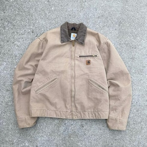 May include: A tan work jacket with a brown collar and a zipper closure. The jacket has two front pockets and a small logo patch on the chest. The jacket is made of a durable, heavy-duty fabric.