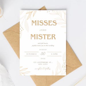 May include: A wedding invitation with the words "Misses and Mister" in gold lettering. The invitation includes the date, time, and location of the wedding, with floral accents. It is placed on a brown envelope.
