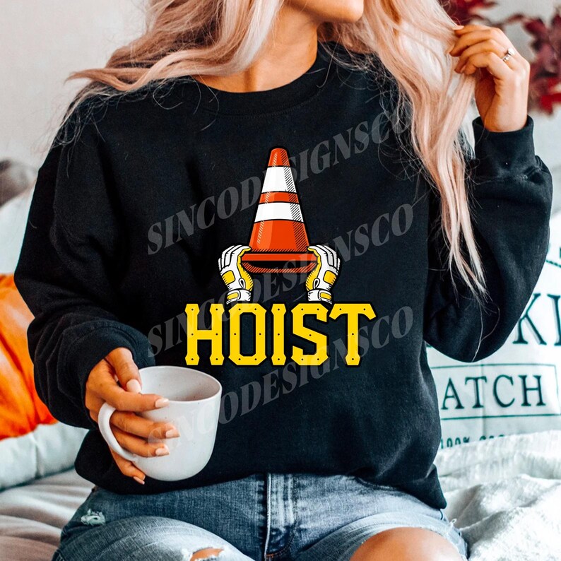 May include: Black sweatshirt with a graphic of a traffic cone held by gloved hands, with the word "HOIST" in yellow block letters. The cone is orange and white. The sweatshirt is a crew neck.