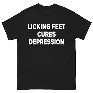 Peut inclure: T-shirt noir avec le texte blanc "LICKING FEET CURES DEPRESSION" imprimé sur le devant. Le t-shirt est de style col rond et à manches courtes.